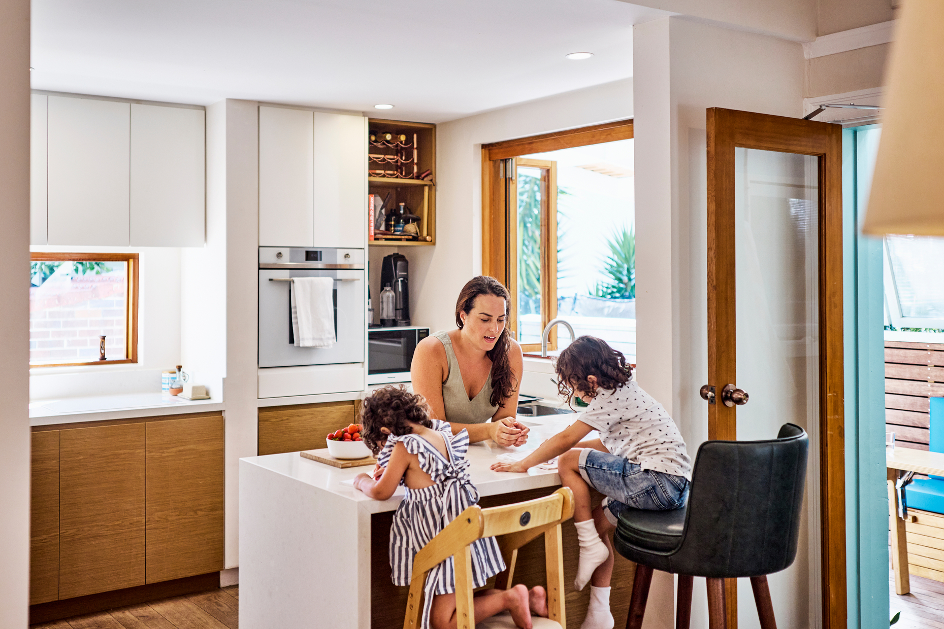 Mother and her young children in the kitchen of their home.
